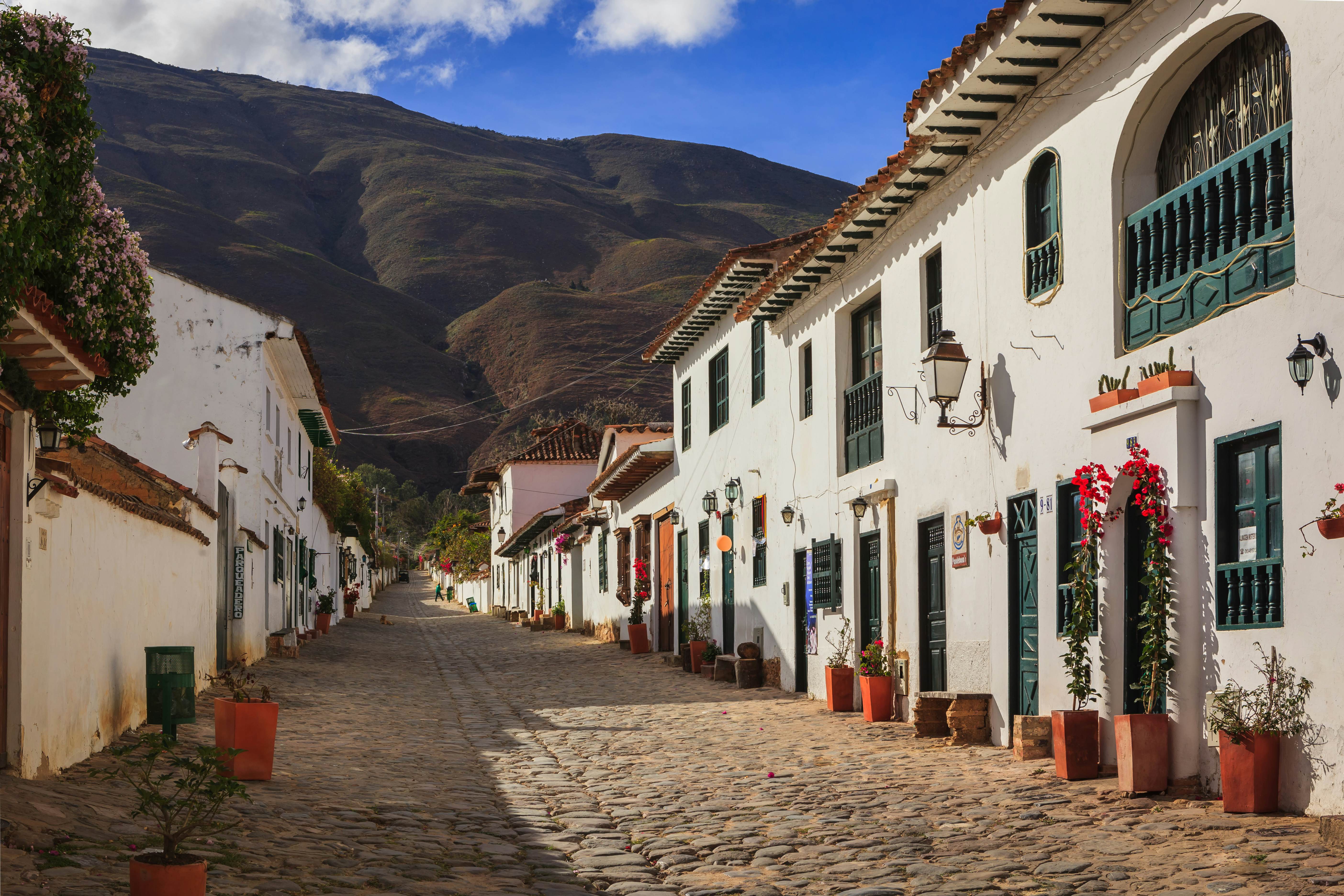 Villa de Leyva, Colombia - September 14, 2014:  It is Sunday morning in Villa de Leyva and Calle or Street 14 is almost lifeless.  The shops and restaurants will open; but, only towards noon.  Founded in 1572 and located at just over 7000 feet above sea level on the Andes Mountains, Villa de Leyva was declared a National Monument in 1954 to protect it's colonial architecture and heritage. It is located in the Department of Boyaca, in the South American country of Colombia.  In the background are the always present Andes Mountains.  Photo shot in the morning sunlight; horizontal format. Copy space.